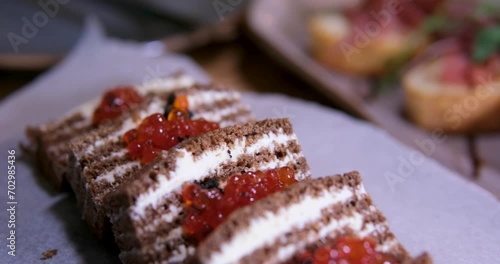 sandwich with red caviar on black bread with butter, smeared black bread in the form of a cake on parchment paper in a restaurant, serving delicious, beautiful black and red caviar on a plate photo