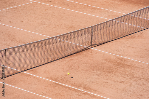Isolated tennis ball on the clay surface of the tennis court
