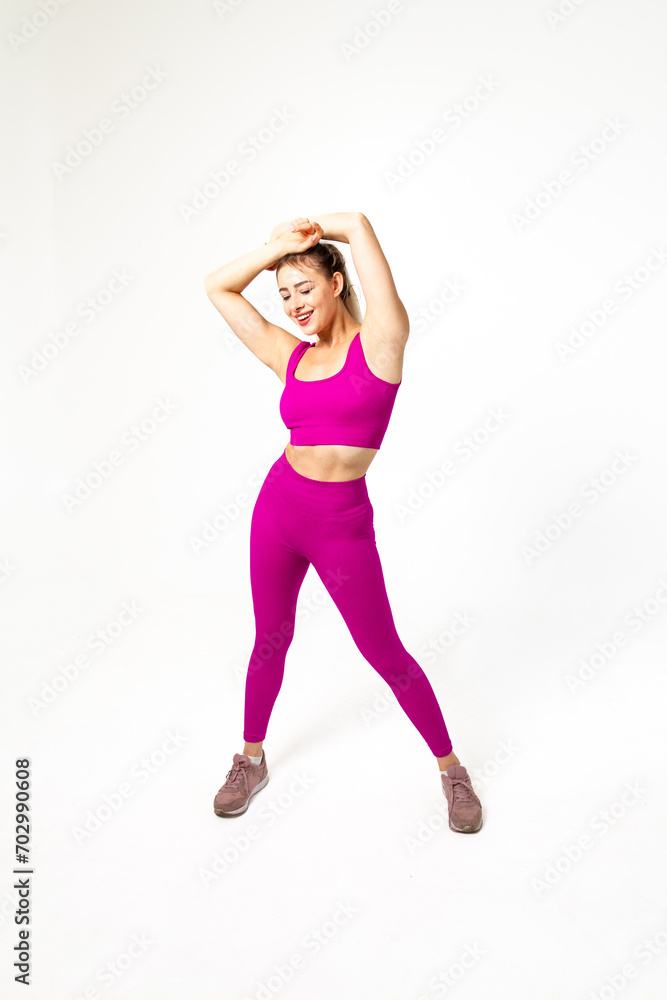 Smiling woman in vibrant pink sports outfit with closed eyes and hands over head