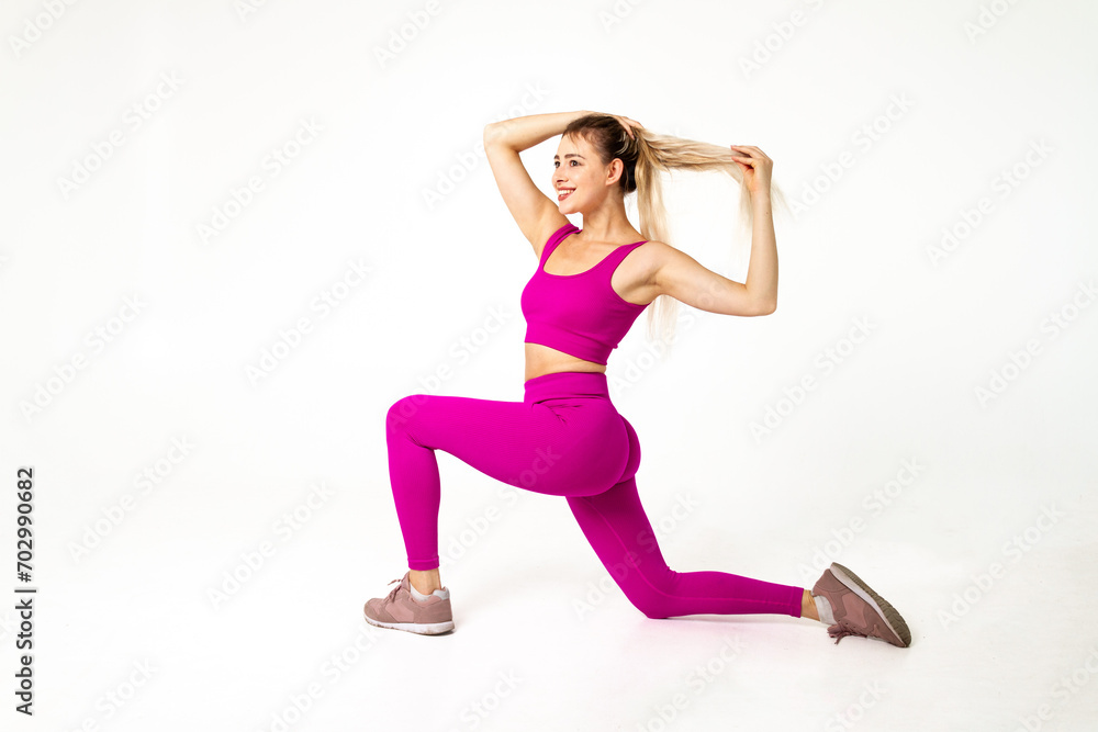 Woman in vibrant pink sports outfit one knee on floor, other bent in front and hands in hairs Woman in vibrant pink sports outfit one knee on floor, other bent in front and hands in hairs