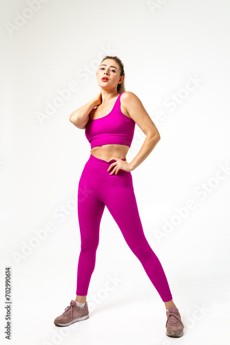 Woman in vibrant pink sports outfit with one hand on neck and other on hips