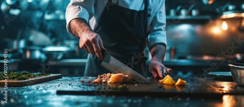 Chef sharpening knife in dark kitchen photo