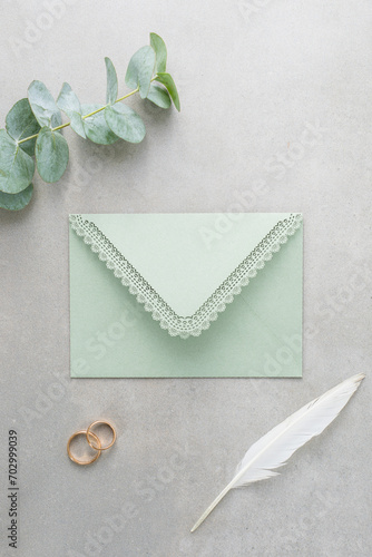 Wedding background, green invitation envelope on a gray background, top view