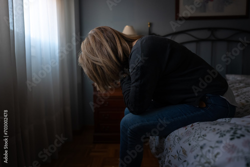Woman sitting on bed with hands on face suffering from tiredness and depression © josemiguelsangar