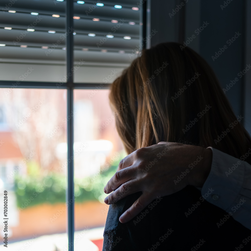 Man's hand on the shoulder of a woman suffering from depression and sadness.