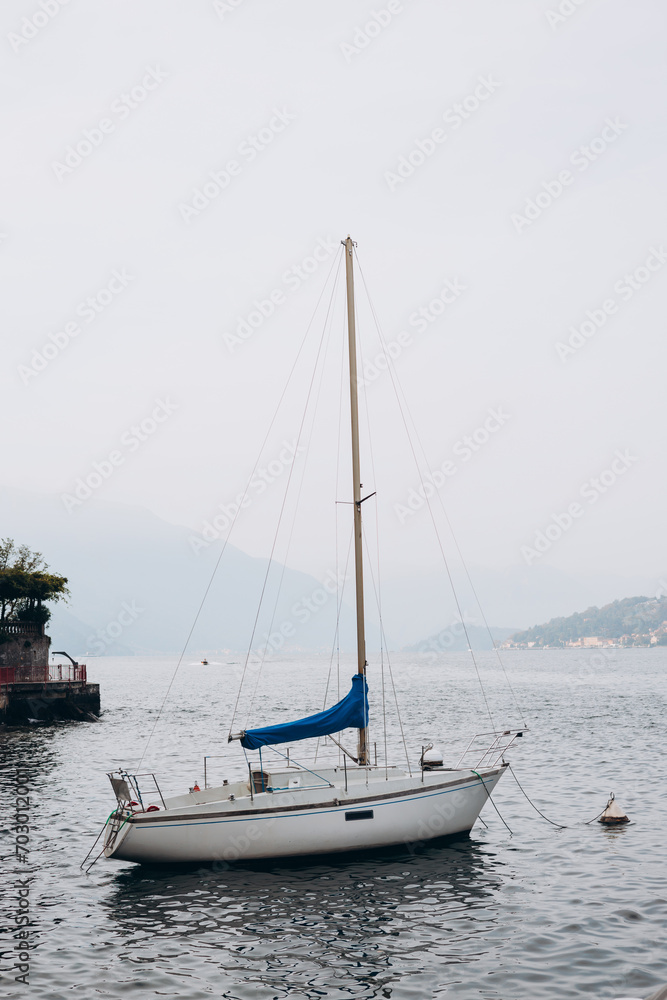 White sailing boat on lake Como. Water sports. The concept of a luxurious lifestyle, mountain background White sailing boat on lake Como. Water sports. The concept of a luxurious lifestyle, mountain background