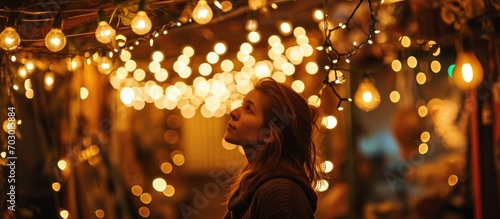 A lady in a dim room amidst numerous string lights.