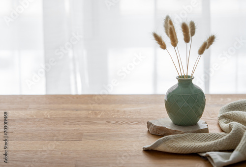 Wooden oak table top with a green vase with dry flowers and napkin. #703019469