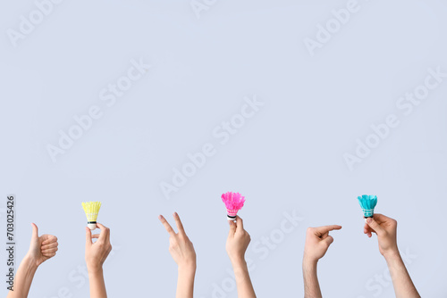 Female hands with shuttlecocks on grey background