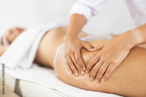 Female masseuse doing thigh massage closeup to young woman client