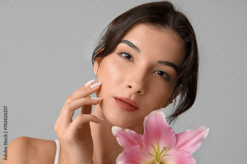 Beautiful young woman with pink lily flower on grey background, closeup Beautiful young woman with pink lily flower on grey background, closeup