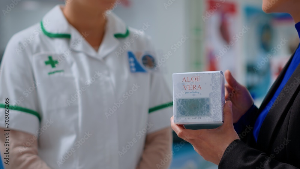 Close up of qualified pharmacist in dispensary offering shopper aloe vera product for treating sun burns. Healthcare professional in chemist store helping client with pain calming balm Close up of qualified pharmacist in dispensary offering shopper aloe vera product for treating sun burns. Healthcare professional in chemist store helping client with pain calming balm