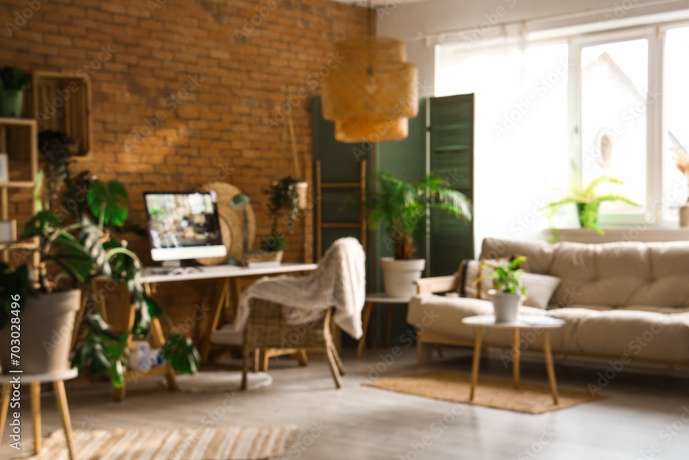 Blurred view of office with workplace, green plants and sofa