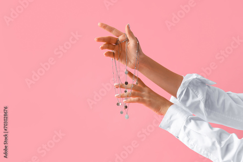 Woman with silver necklace on pink background