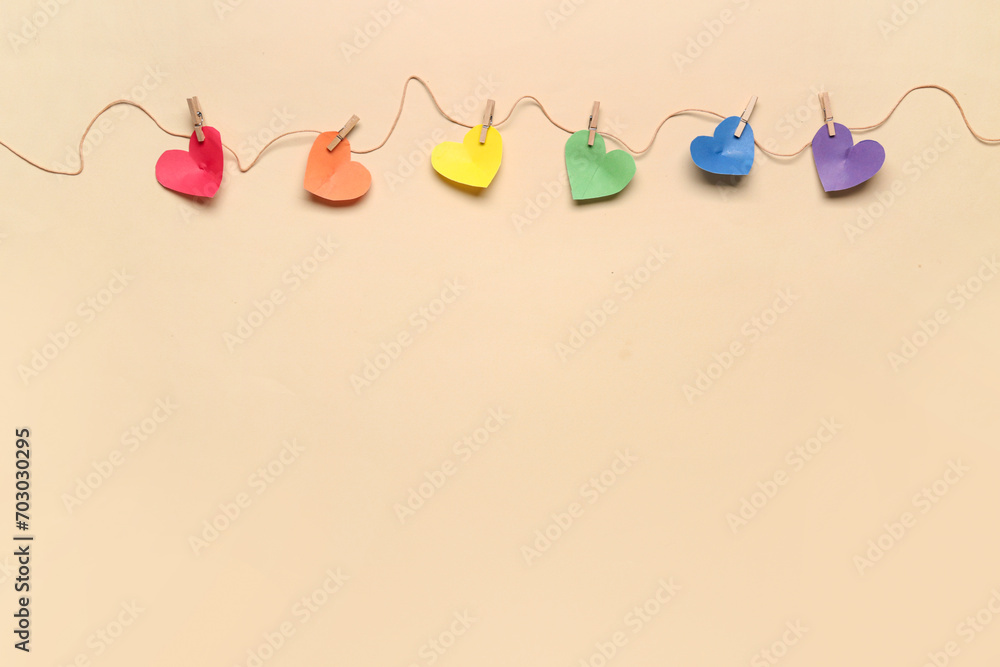 Paper hearts in colors of LGBT flag hanging on rope against color background. Valentines Day celebration Paper hearts in colors of LGBT flag hanging on rope against color background. Valentines Day celebration