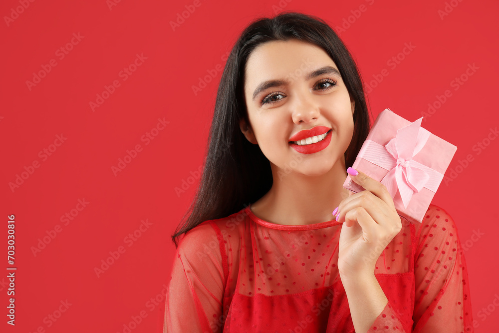 Beautiful young woman with gift for Valentine's day on red background Beautiful young woman with gift for Valentine's day on red background