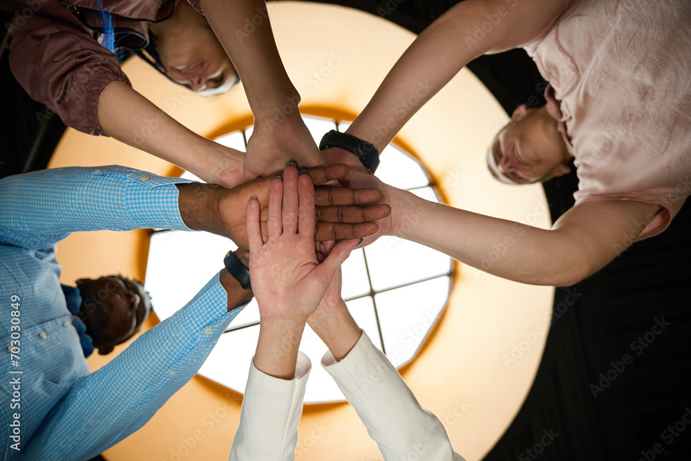Hardworking colleagues folding hands together as symbol of friendly team Hardworking colleagues folding hands together as symbol of friendly team