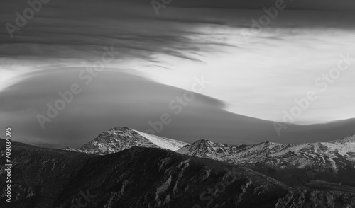 Black and white view of snow-capped Mulhacén (Granada, Spain), the highest mountain in the Iberian Peninsula, with spectacular lenticular clouds at sunset