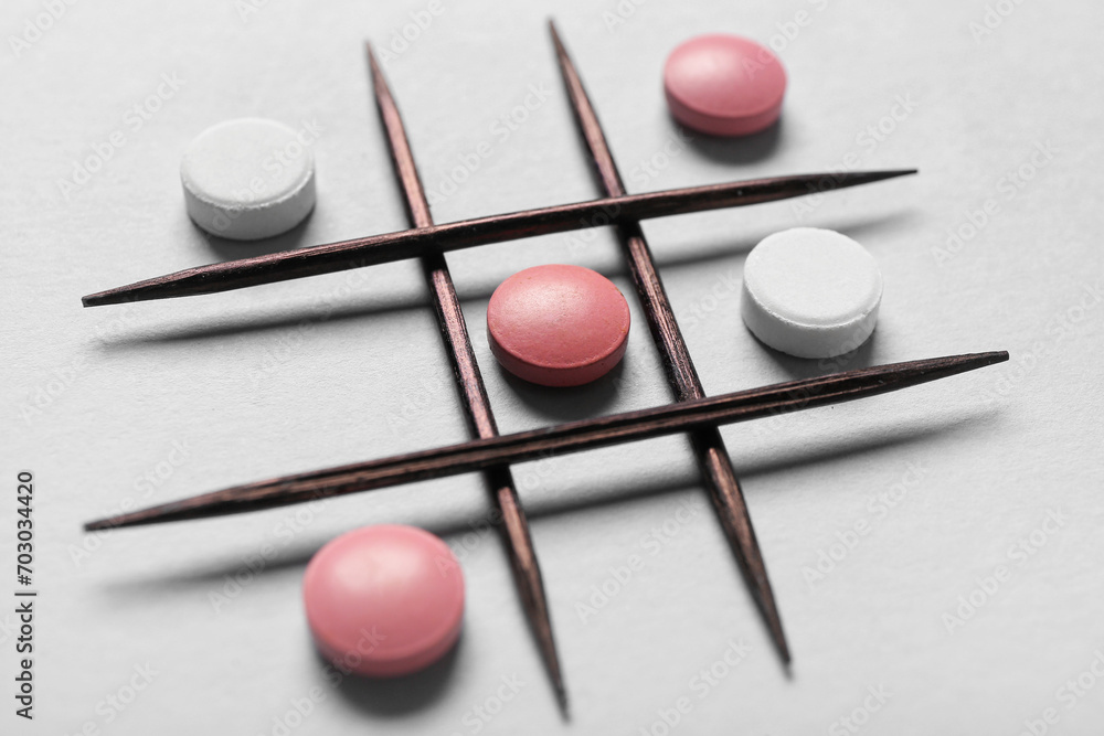 Tic tac toe game with pills and toothpicks on grey background, closeup Tic tac toe game with pills and toothpicks on grey background, closeup