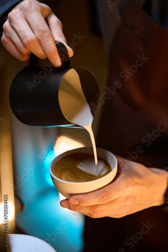 Barista pouring froth milk in coffee making caffe latte art serve to customer