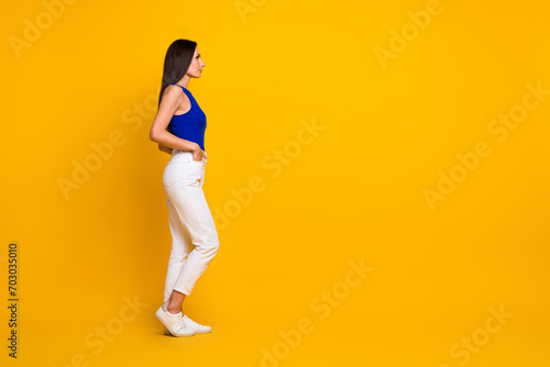 Full length photo of positive good mood woman wear blue top looking empty space isolated yellow color background