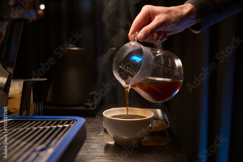 Barista pouring hot coffee into cup placed on counter in cafe beverage