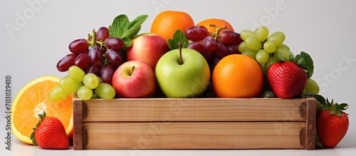 Fresh assorted fruit in a wooden box on white.