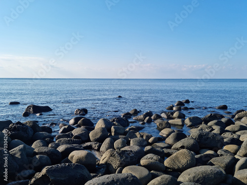 This is a Jeju beach with blue skies and basalt rocks © binimin