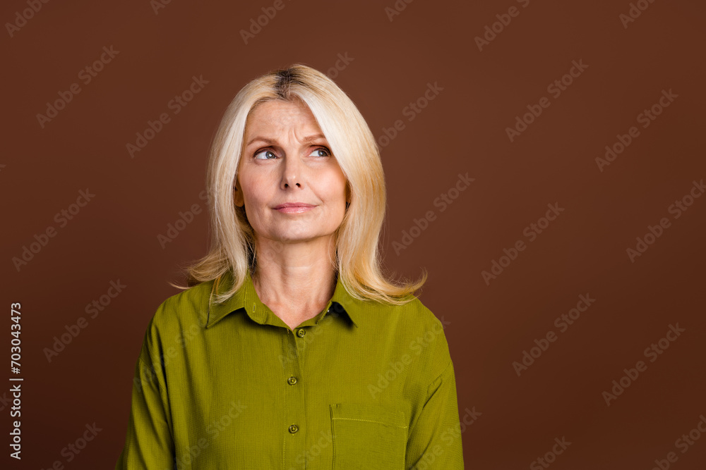 Photo of minded clever person dressed khaki shirt look at confusing proposition empty space isolated on dark brown color background Photo of minded clever person dressed khaki shirt look at confusing proposition empty space isolated on dark brown color background