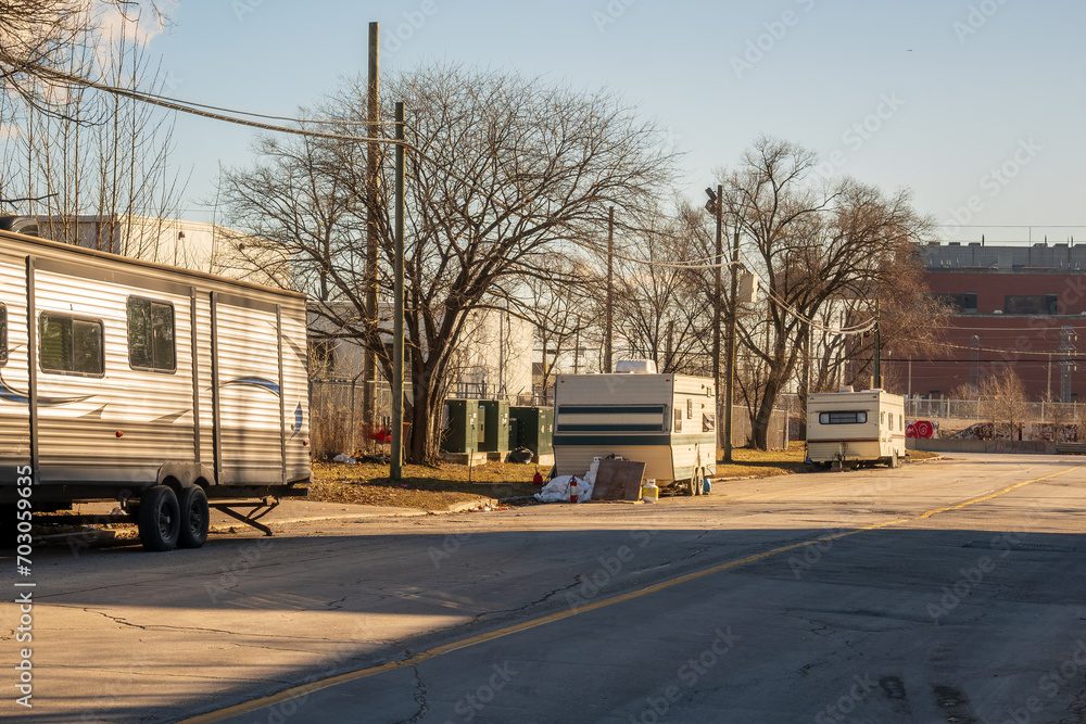housing crisis: older travel trailers setup on a public street in an industrial section of a big north american city (toronto).