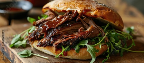 Smoked British beef brisket with barbecue sauce, on a bun with watercress leaves. photo