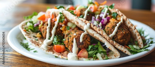 Gluten-free pita filled with flavorful chickpea falafel, chopped salad, and tahini drizzle. photo