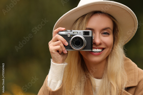 Autumn vibes. Smiling woman with camera taking photo outdoors, space for text © New Africa
