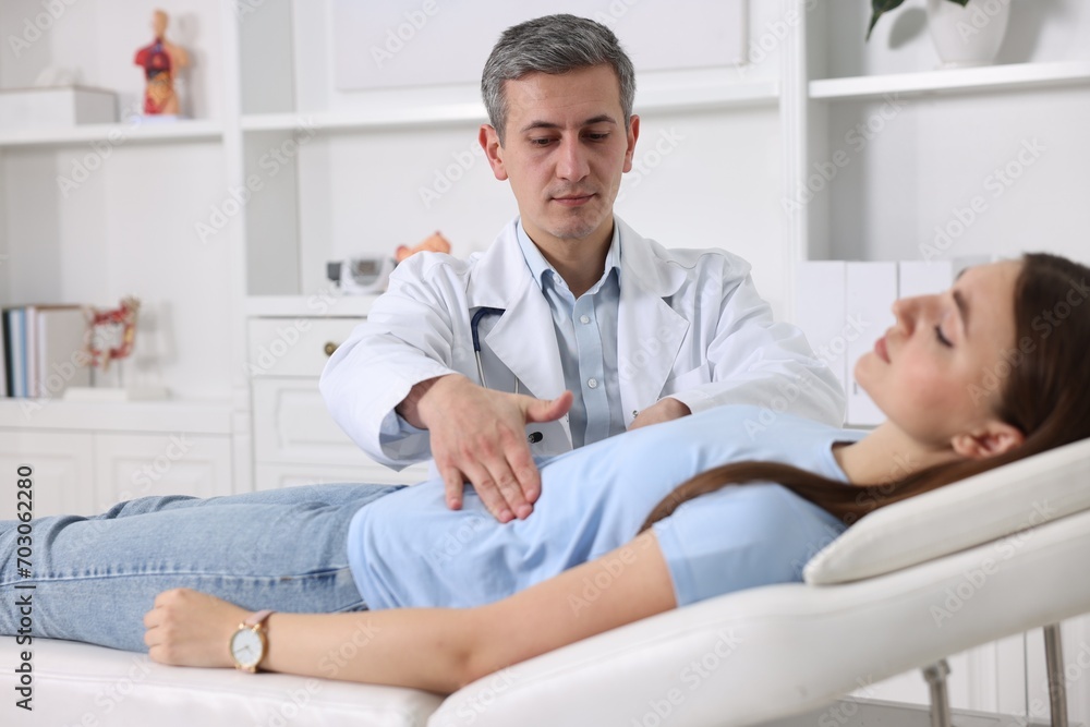 Fototapeta premium Gastroenterologist examining patient with stomach pain on couch in clinic