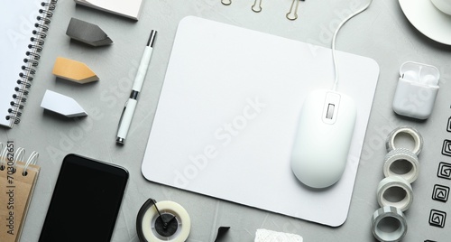 Flat lay composition with wired computer mouse and stationery on light grey table photo