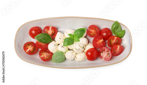 Plate of delicious Caprese salad with tomatoes, mozzarella, basil and spices isolated on white, top view