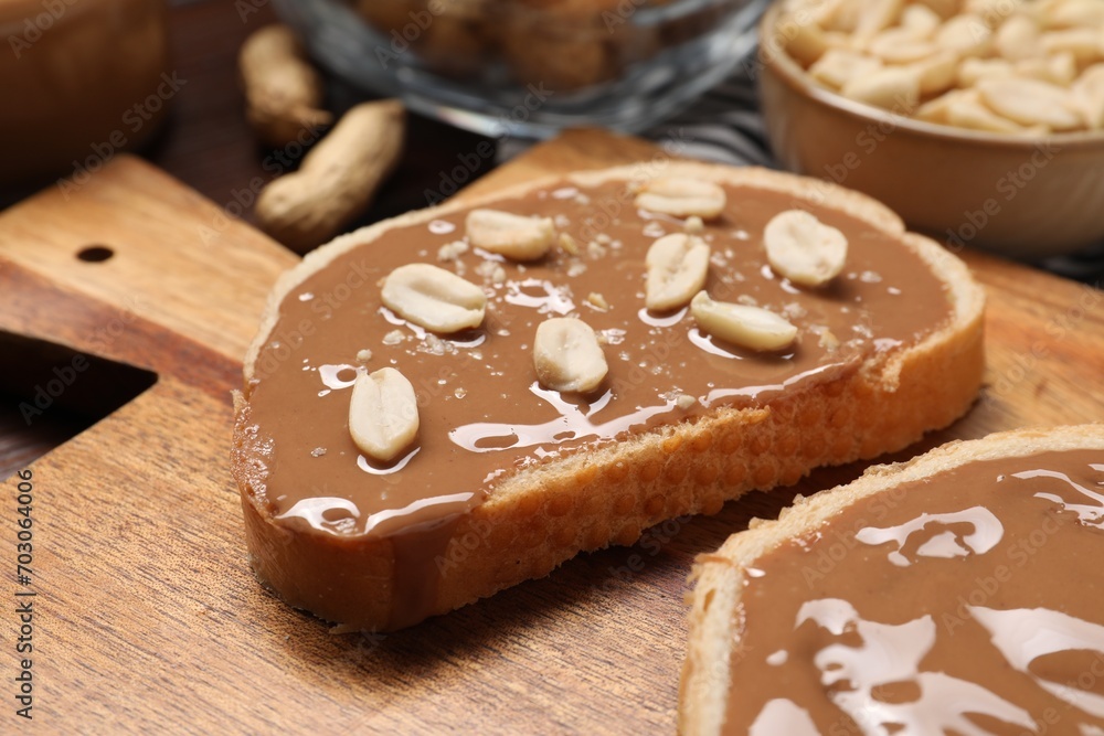 Toasts with tasty nut butter and peanuts on wooden board, closeup Toasts with tasty nut butter and peanuts on wooden board, closeup