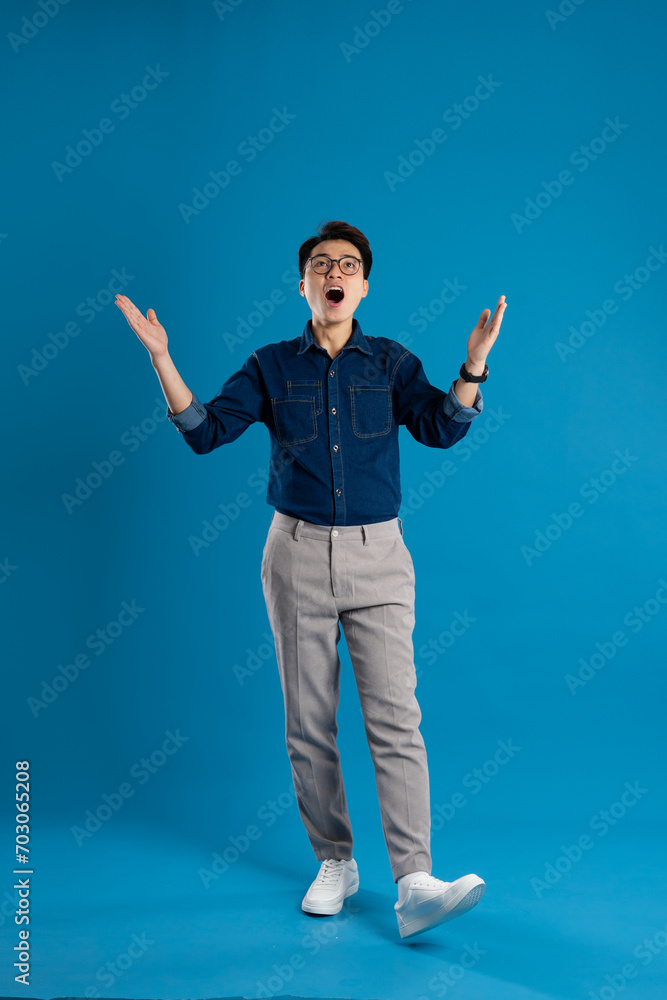 Portrait of young Asian business man posing on blue background Portrait of young Asian business man posing on blue background