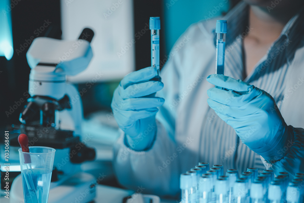 Technician holding tube test in the research laboratory, chemist's hand taking a solution sample tube from a rack with machines of analysis in the lab, Dripping liquid from pipette into tube. Technician holding tube test in the research laboratory, chemist's hand taking a solution sample tube from a rack with machines of analysis in the lab, Dripping liquid from pipette into tube.