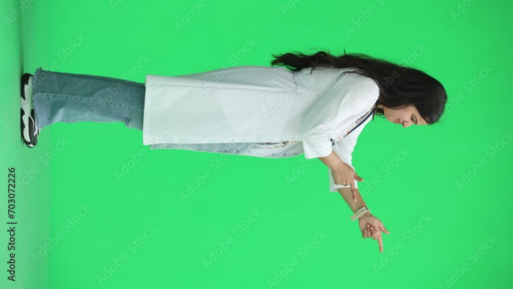 A female doctor, on a green background, in full height, points to the side, profile A female doctor, on a green background, in full height, points to the side, profile