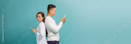 Fotografie Wife watching her husband using mobile phone, spying her boyfriend while man typ