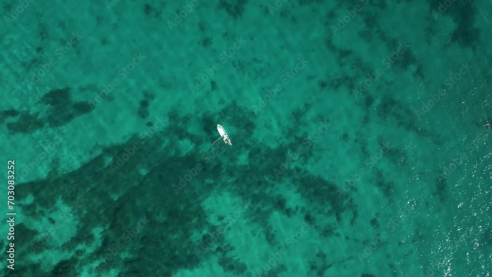 Lone boat floating on wide open turquoise ocean - Drone top down view Lone boat floating on wide open turquoise ocean - Drone top down view