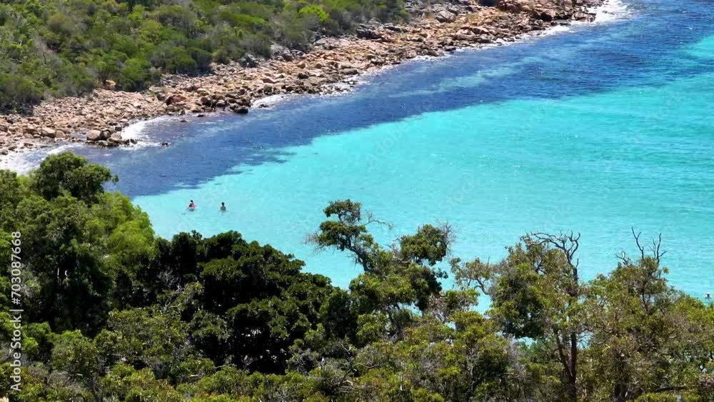 People enjoying water activities at pristine beach with clear turquoise waters People enjoying water activities at pristine beach with clear turquoise waters