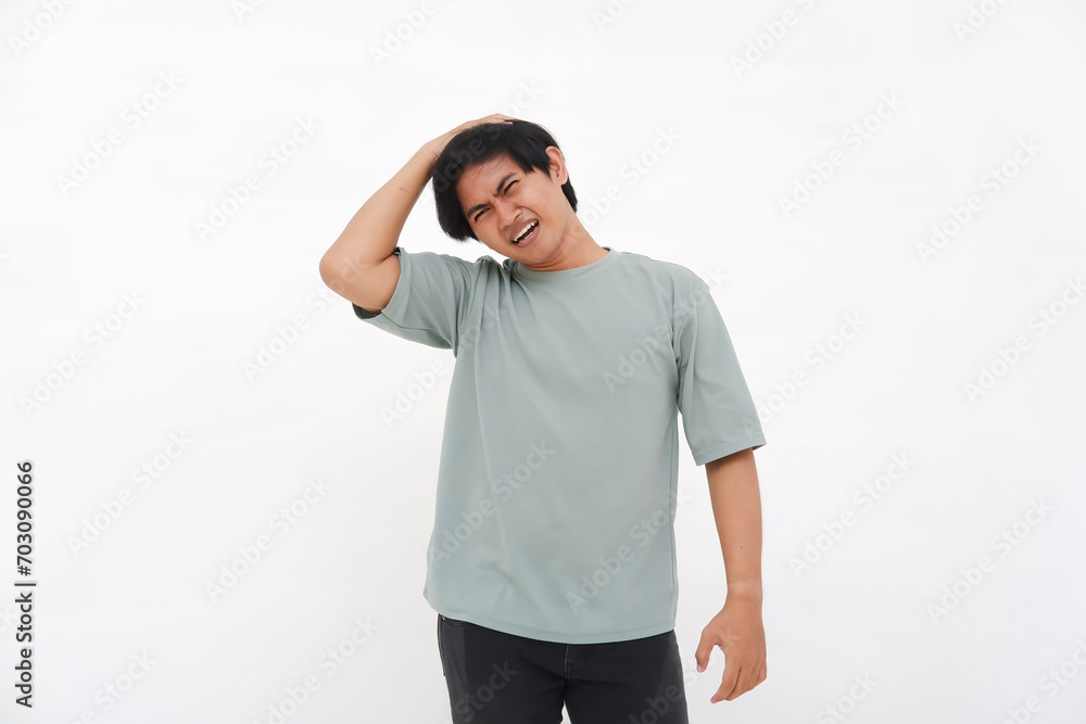 A young Asian man holding his head, experiencing a headache looking confused, depressed, and frustrated A young Asian man holding his head, experiencing a headache looking confused, depressed, and frustrated