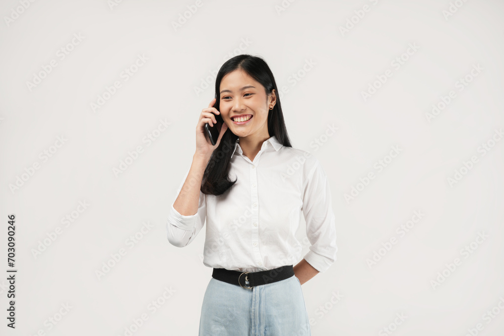 An Asian woman smiles while holding a phone, exuding confidence. Captured in a bright studio, this image aims to represent connectivity and modern lifestyle choices. An Asian woman smiles while holding a phone, exuding confidence. Captured in a bright studio, this image aims to represent connectivity and modern lifestyle choices.