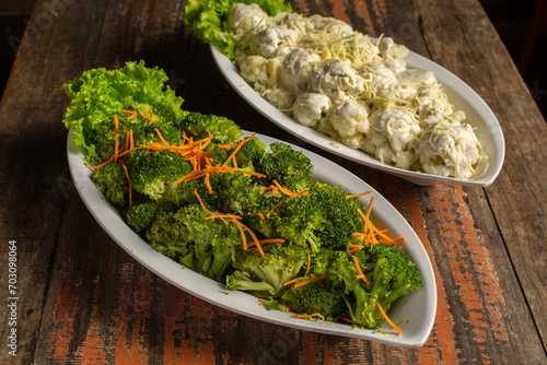 Platters with broccoli and cauliflower on wooden background.