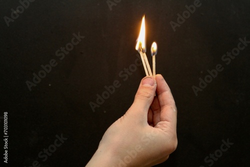  Hand holding three lit matches against dark background