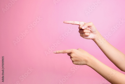 Two hands points to something with index finger over pink background, cut out photo