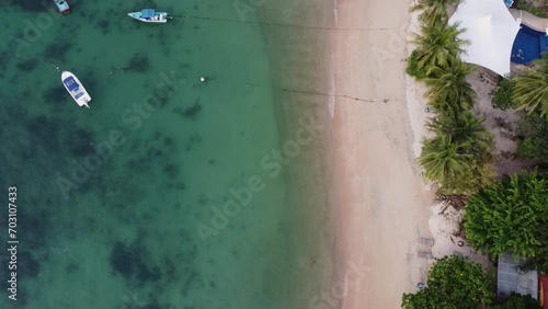 Drone shot top down of an idealic beach and palm trees and a small fishing boat  photo