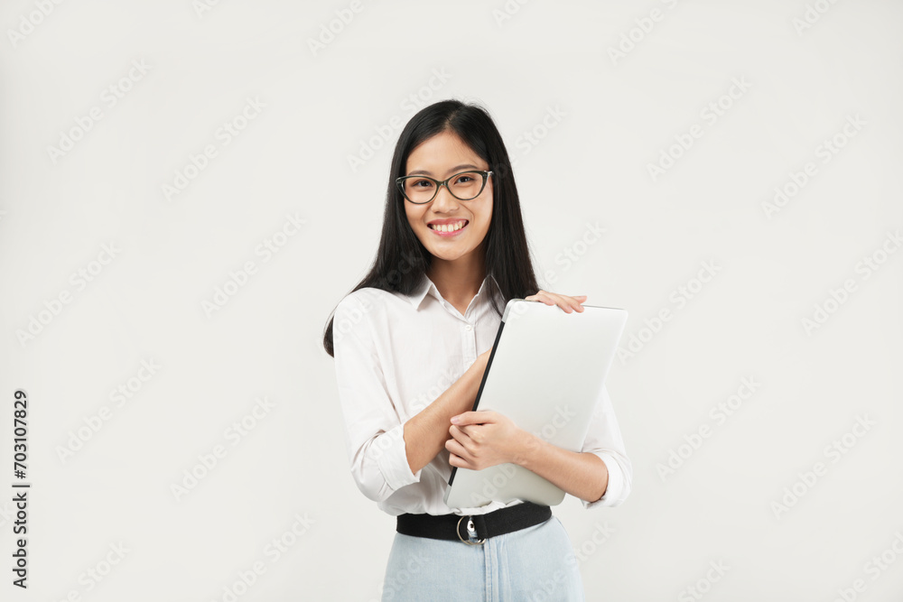 Portrait of a young Asian millennial college student holding a laptop, wearing a white shirt and glasses, isolated on a white background. Student concept. Portrait of a young Asian millennial college student holding a laptop, wearing a white shirt and glasses, isolated on a white background. Student concept.